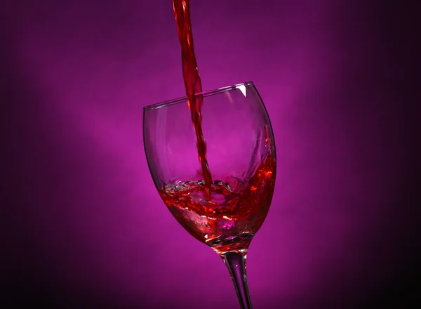 Víno, nalévání skla na tmavě fialové pozadí — Stock fotografie