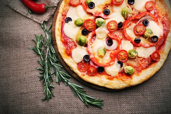 Deliciosa pizza con queso y verduras sobre fondo de saco —  Fotos de Stock