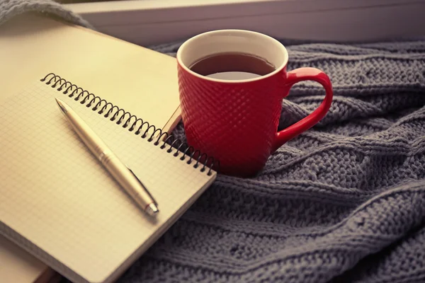 Rote Tasse Tee, Buch und warm gestrickter Karo auf der Fensterbank, Nahaufnahme — Stockfoto