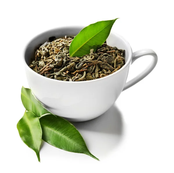 Cup with dry tea and green leaves, isolated on white — Stock Photo, Image