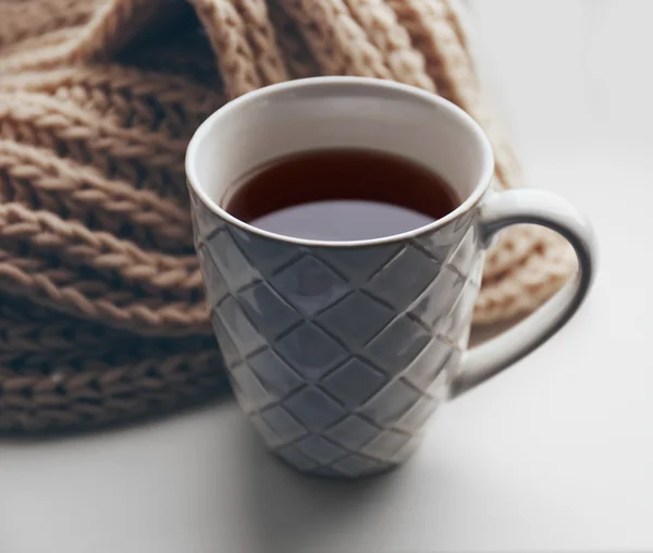 Tasse de thé et foulard tricoté chaud sur le rebord de la fenêtre, gros plan — Photo