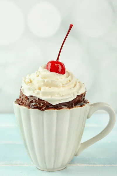 Pastel de taza de chocolate con crema y cereza en una mesa —  Fotos de Stock