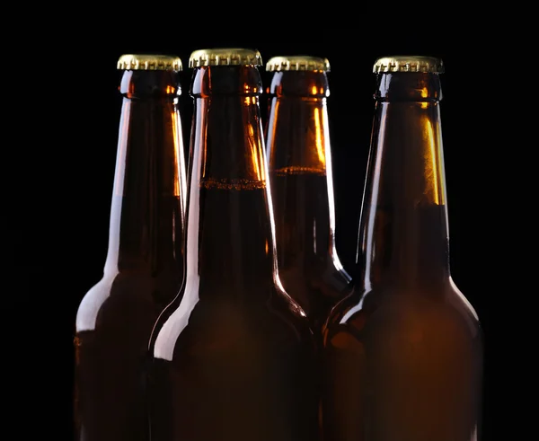 Four bottles of beer on black background — Stock Photo, Image