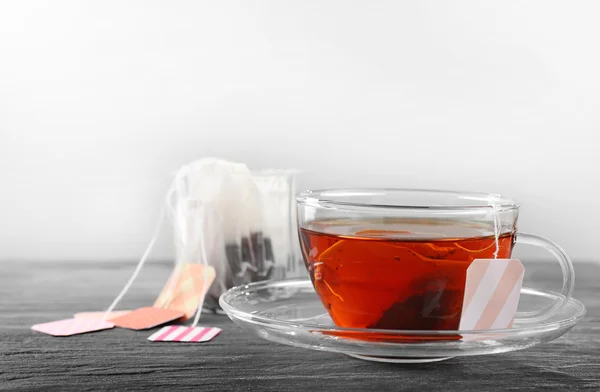 Taza de té con bolsas de té sobre fondo de madera sobre fondo gris — Foto de Stock