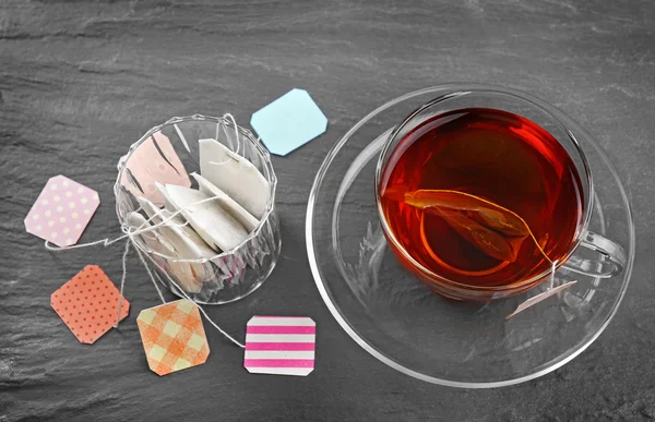 Tazza di tè con bustine di tè su sfondo grigio — Foto Stock