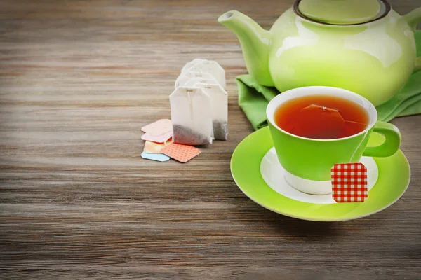 Taza de té con bolsas de té y tetera sobre fondo de mesa de madera —  Fotos de Stock