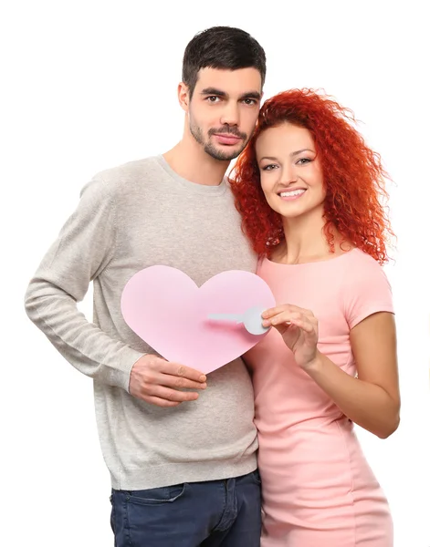 Junges verliebtes Paar mit rosa Herz und Schlüssel aus Papier, isoliert auf weiß — Stockfoto