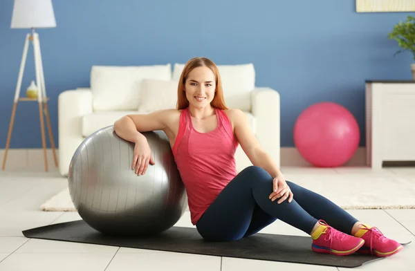 Young sportswoman sitting with ball — Stock Photo, Image