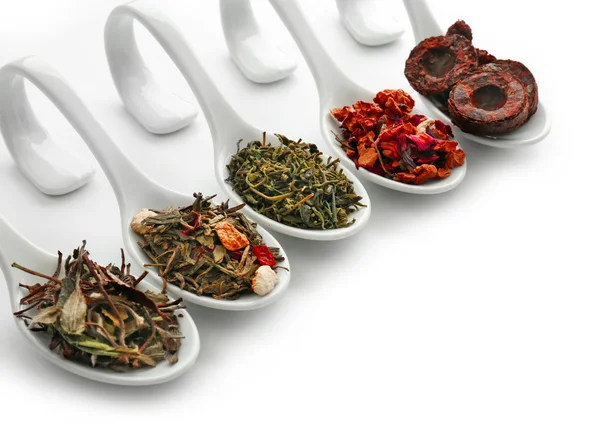 Différentes sortes de thé sec dans des cuillères en céramique, isolé sur blanc — Photo