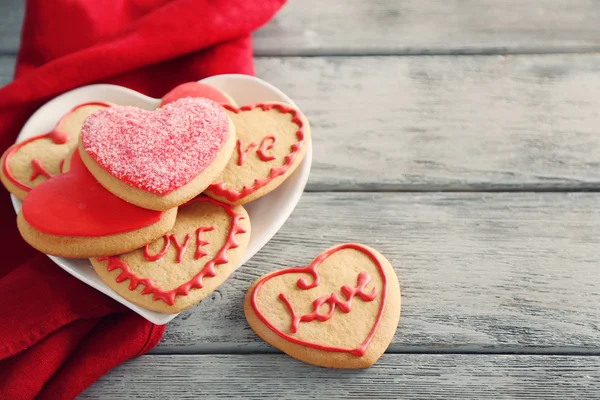 Sortiment z lásky cookies s červenou látkou na pozadí šedé dřevěný stůl — Stock fotografie