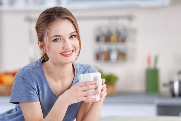 Mujer sosteniendo taza en la cocina — Foto de Stock