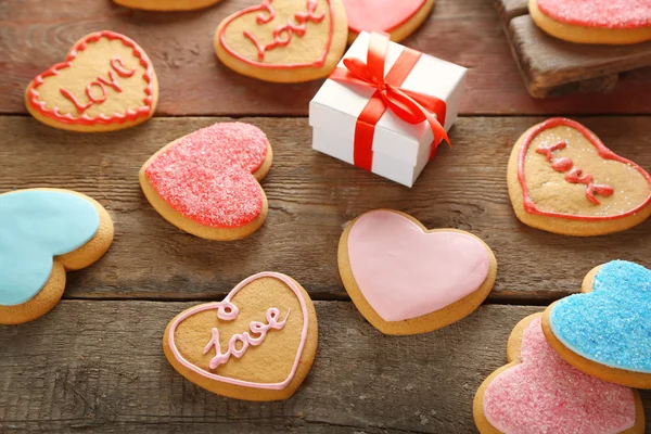 Barevné Valentine srdce cookies s krabičce na dřevěné pozadí — Stock fotografie