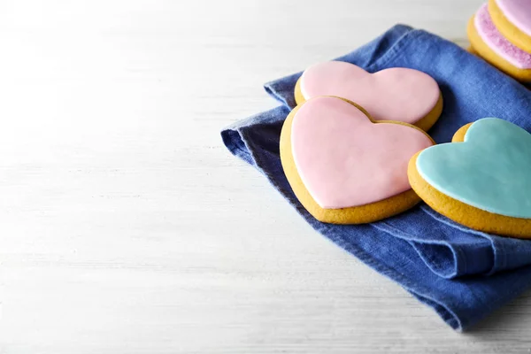 Valentine heart cookies with blue napkin on wooden background