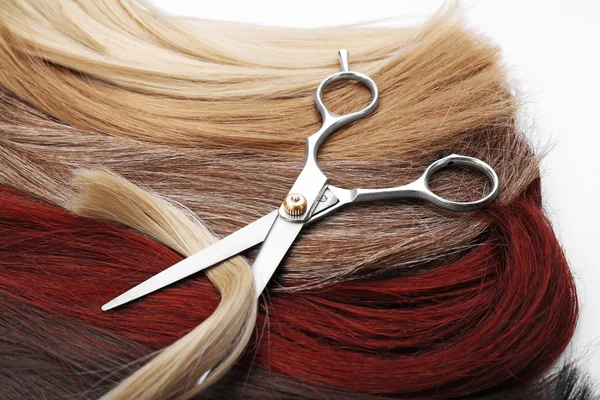 Tijeras de peluquería con mechones varicolores de pelo sobre fondo —  Fotos de Stock