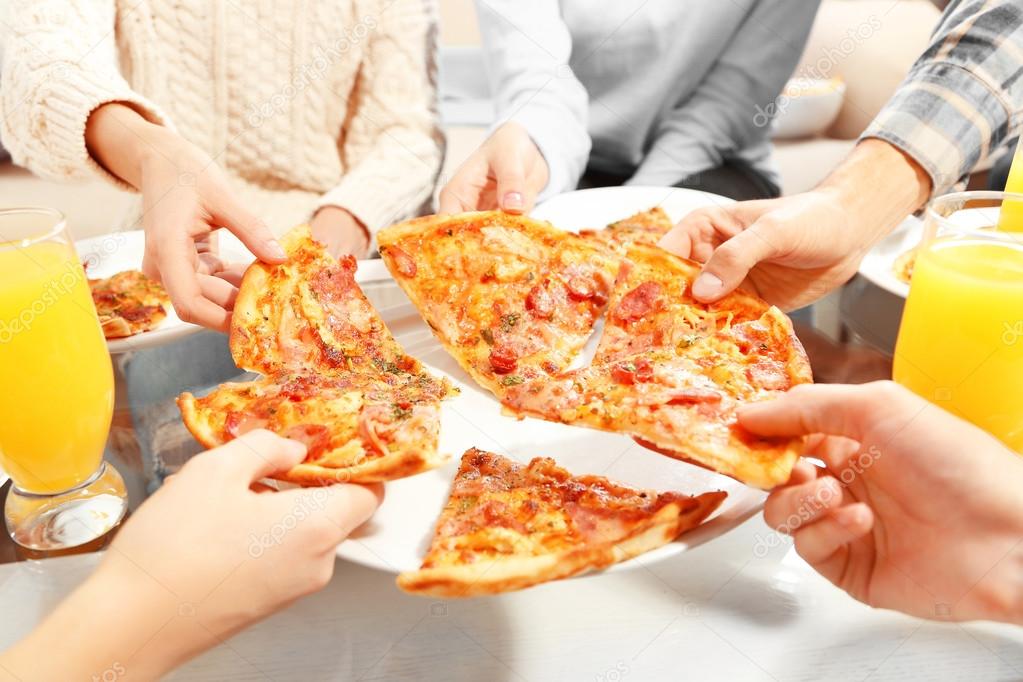 Friends hands holding hot pizza, close up