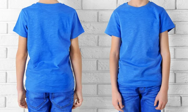 Kleding reclame. Jongen in blauw T-shirt en jeans op bakstenen muur achtergrond — Stockfoto