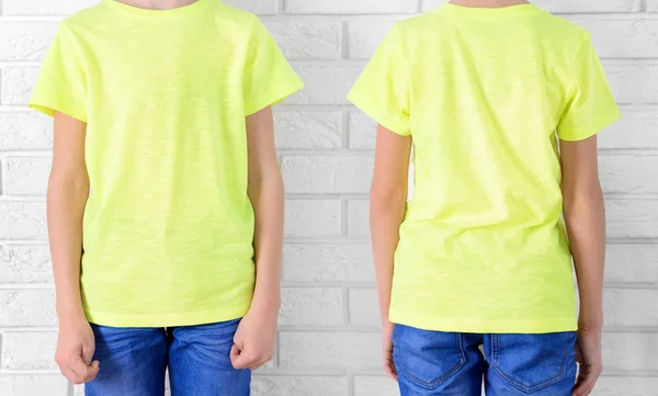 Kleding reclame. Jongen in geel T-shirt en jeans op bakstenen muur achtergrond — Stockfoto