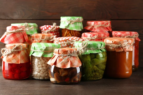 Jars with pickled vegetables and beans on wooden background — Stock Photo, Image