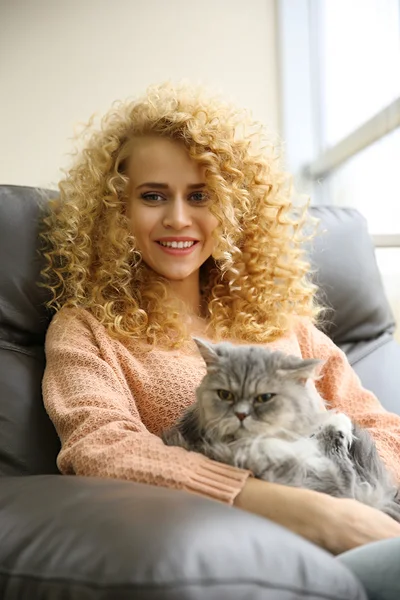 Женщина и кошка на диване в комнате — стоковое фото