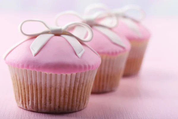 Leckere Cupcakes mit Schleife auf farbigem Holzhintergrund — Stockfoto