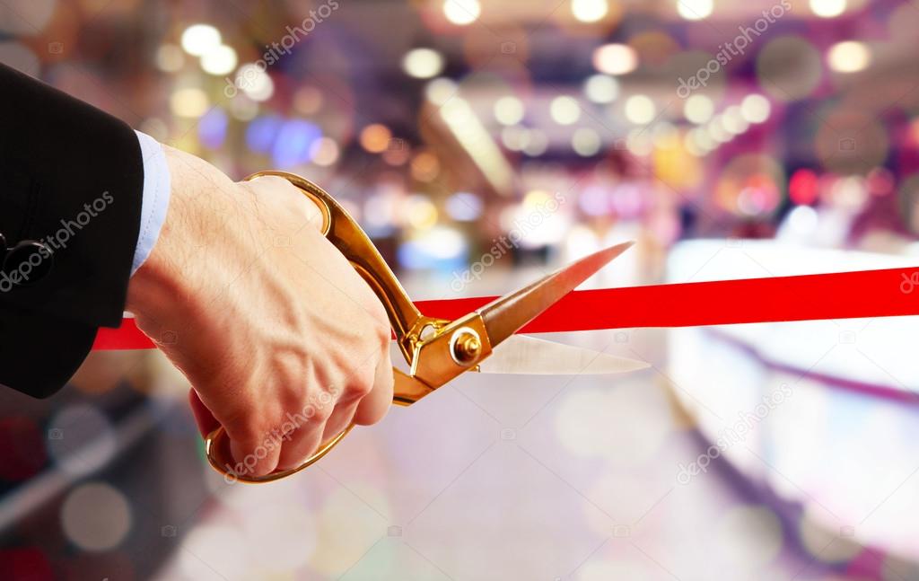 Businessman cutting red ribbon