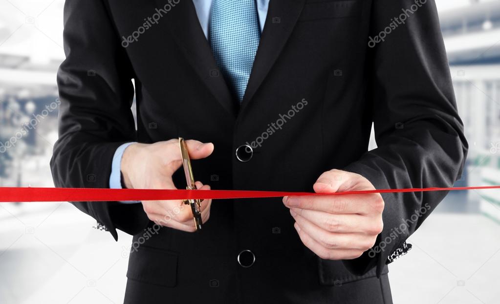 Businessman cutting red ribbon