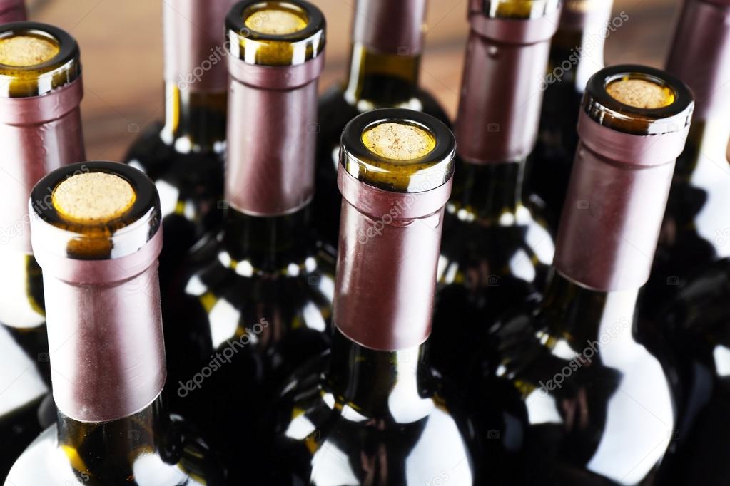 Stacks of wine bottles on wooden background, upside view. Close up