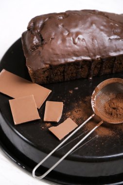 Çikolatalı kek buzlanma ve kakao tozu üzerinde beyaz masa üzerinde pişirme çanağı