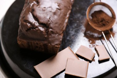 Çikolatalı kek buzlanma ve kakao tozu üzerinde beyaz masa üzerinde pişirme çanağı