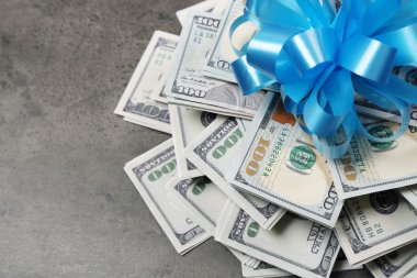 Gri dokulu arka plan üzerinde hediye olarak yay ile dolar yığını