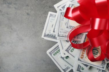 Gri dokulu arka plan üzerinde hediye olarak yay ile dolar yığını