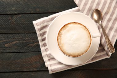 Köpük ve siyah ahşap bir masa kaşık ile sıcak cappuccino fincan