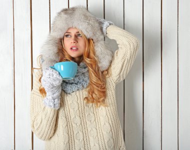 Sıcak bir içecek fincan ile örme onu sıcak giysiler, genç güzel sarışın kadın kış portresi