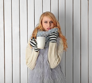 Sıcak bir içecek fincan ile örme onu sıcak giysiler, genç güzel sarışın kadın kış portresi