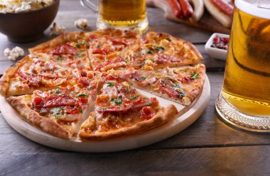 Pizza ve bira cam ahşap masanın üzerine dilimlenmiş, yakın çekim