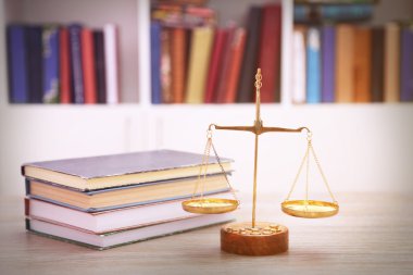 Justice scales with stack of books on wooden table clipart