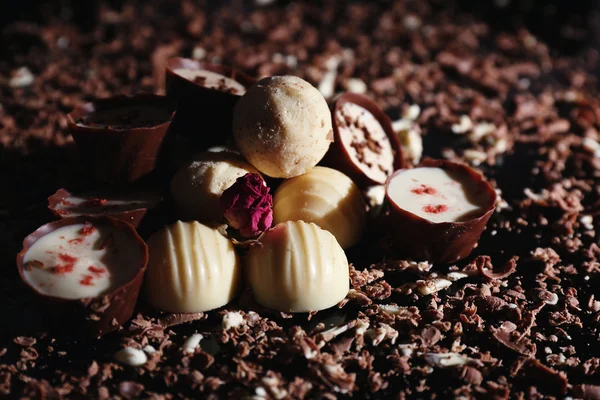 Doces de chocolate sortidas com flocos no fundo preto — Fotografia de Stock