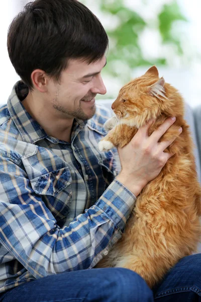 Kabarık kedi kanepede oturan genç adam — Stok fotoğraf