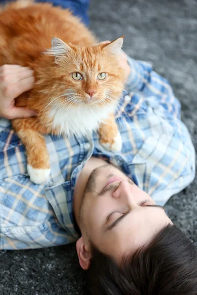 Joven con gato esponjoso acostado en una alfombra —  Fotos de Stock