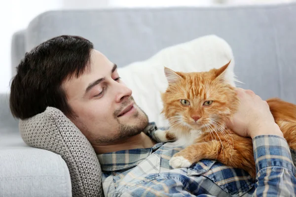 Jeune homme avec chat moelleux couché sur un canapé — Photo