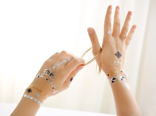 Mains féminines avec des bracelets de maintien de tatouage flash sur fond blanc — Photo