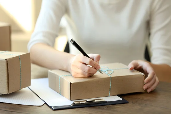 Женщина подписывает бумаги между посылками — стоковое фото