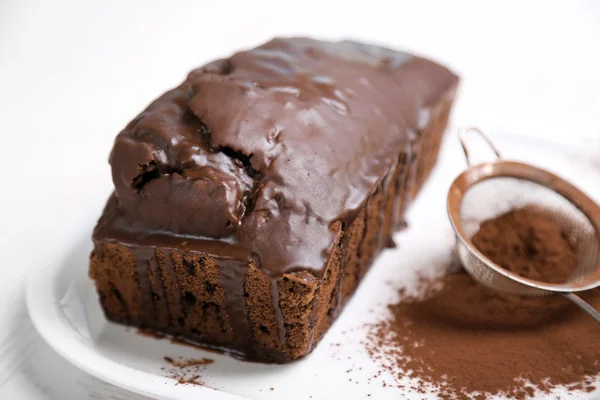 Bolo de chocolate com gelo e cacau em pó na mesa branca — Fotografia de Stock