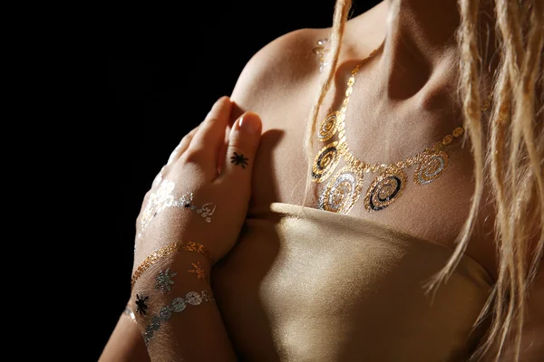 Giovane ragazza bionda con oro e argento flash tatuaggio su sfondo nero — Foto Stock