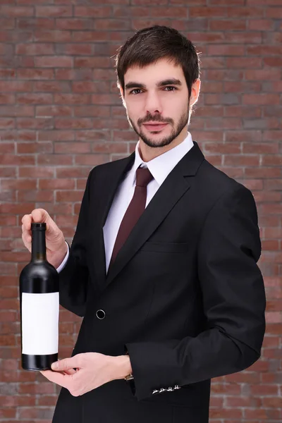 Mężczyzna trzyma butelkę czerwonego wina — Zdjęcie stockowe