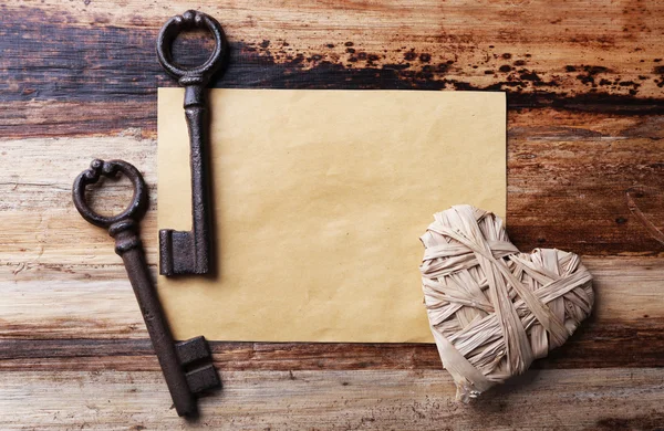 Llave vieja con corazón decorativo y hoja de papel sobre fondo de madera, primer plano — Foto de Stock