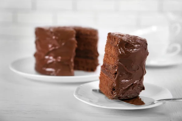 Chocolate cake on plates with a cut piece on unfocused background — Stock Photo, Image