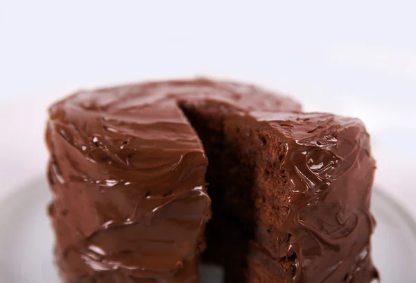 Schokoladenkuchen auf Teller mit einem geschnittenen Stück auf unfokussiertem Hintergrund, Nahaufnahme — Stockfoto