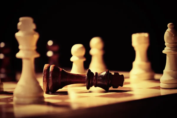 Piezas de ajedrez y tablero de juego sobre fondo oscuro — Foto de Stock