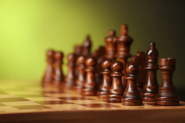 Piezas de ajedrez y tablero de juego sobre fondo verde — Foto de Stock